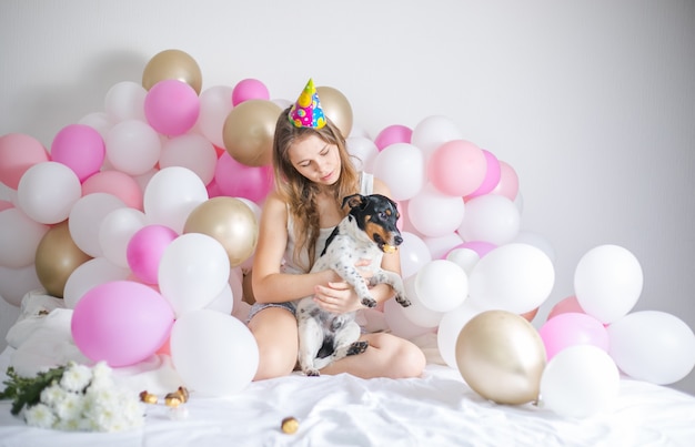 Mooi meisje werd wakker omringd door ballonnen op de dag van de verjaardag met haar hond