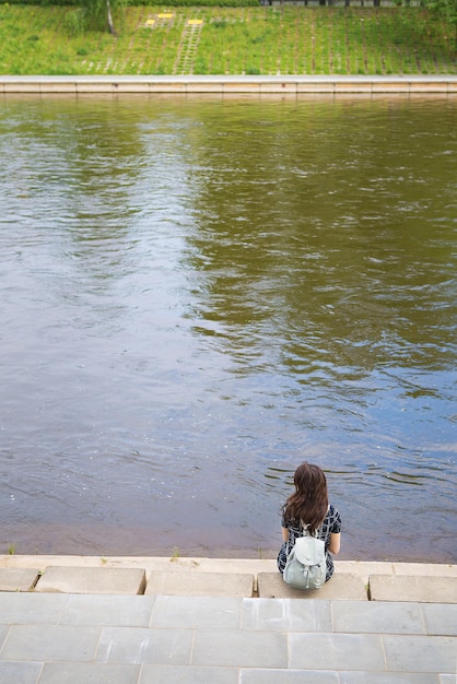 Mooi meisje zit en kijkt naar de rivier Vilnius, Litouwen