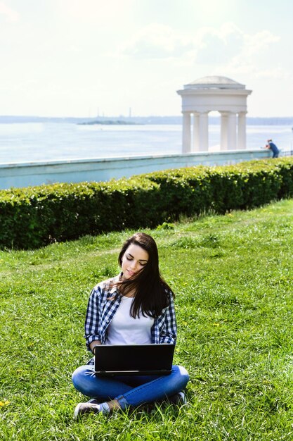 Mooi meisje zit in het park met een laptop