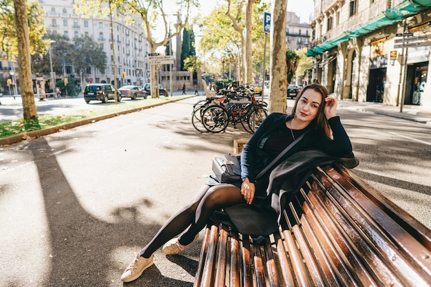 Foto mooi meisje zittend op een bankje in het park in europa
