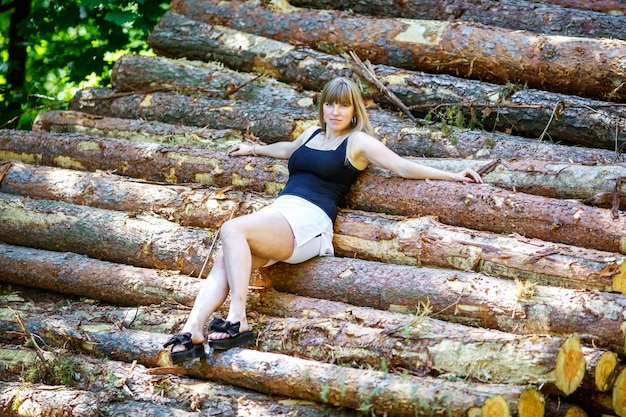 Mooi meisje zittend op gesneden boomstammen in het bos