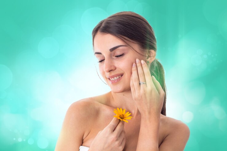 Mooi meisje zorgt voor haar huid met gele bloem in handen geïsoleerd op een witte achtergrond. Gezondheidszorgconcept. Lichaamsverzorgingsconcept. Jonge vrouw met een gezonde huid.
