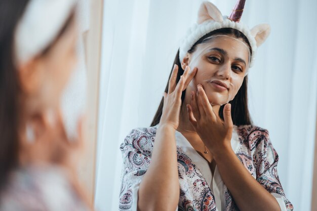 Mooi model dat cosmetische crèmebehandeling op haar gezicht toepast