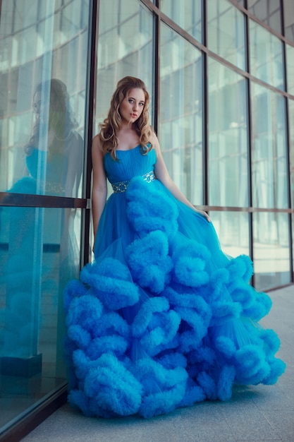 Mooi model in een blauwe jurk over neutrale achtergrond