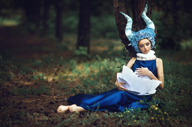 Mooi model is poseren in een bos met blauwe hoorns