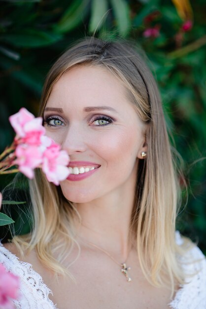 Foto mooi model meisje, met bloemen pioen in de buurt van het gezicht. cosmetica, schoonheid, make-up, bruiloft en cosmetologie.