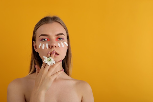 Mooi modelmeisje met bloem op gele achtergrond