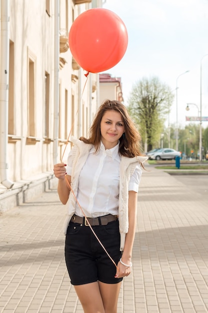 Mooi modemeisje met rode ballon op straat