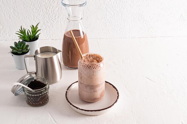 Mooi modern glas met heerlijke aromatische koffie latte of cappuccino met ingrediënten voor het koken op een witte achtergrond Planten stilleven