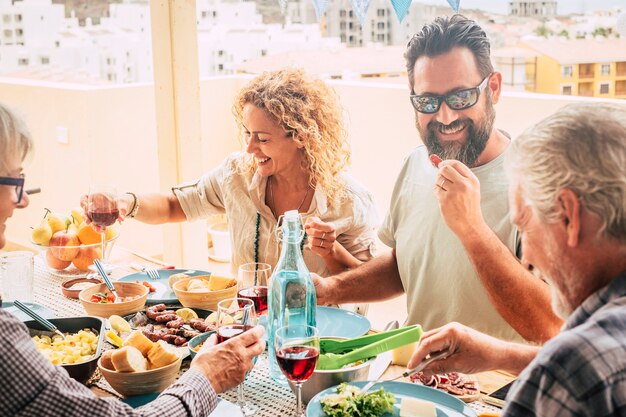 Mooi moment van gezinslevensstijl thuis eten en drinken van eten of drinken thuis op tafel - man met zonnebril die groenten tovert - tafel vol eten en salade buiten