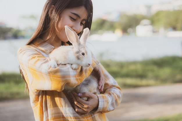 Mooi mooi portret van jonge aziatische vrouw persoon met schattig konijn in huisdier en dierenverzorging concept gelukkig vrouwelijk konijntje houden op natuur buiten veld met vriendschap pasen concept