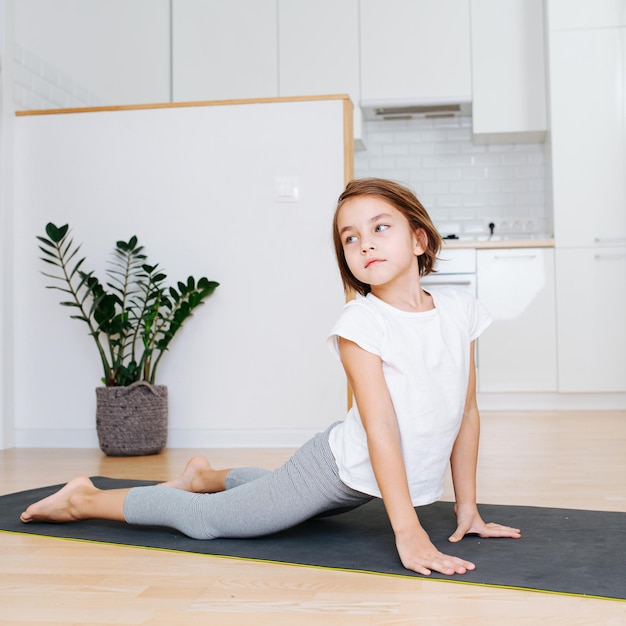 Mooi negenjarig meisje dat thuis yoga doet op een mat Opwaarts gerichte hond