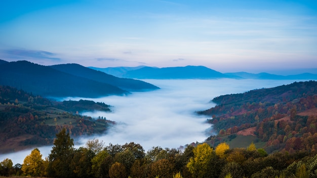 Mooi ochtendlandschap met de herfst mistige bergen.