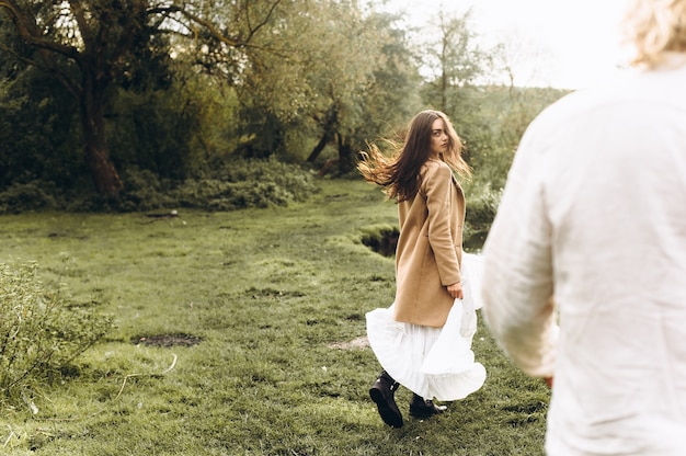 mooi paar gekleed in bohostijl die in het zonnige bos lopen