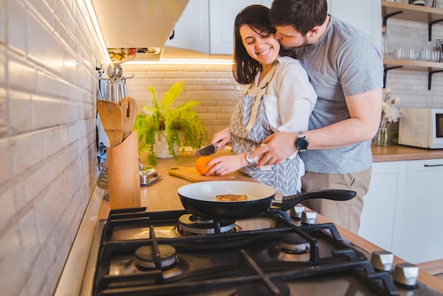 Mooi paar knuffelen in de keuken tijdens het ontbijt koken