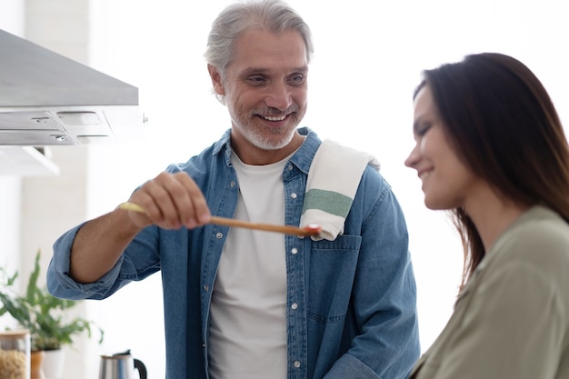 Mooi paar. Man die vrouw voedt en glimlacht terwijl hij thuis in de keuken kookt