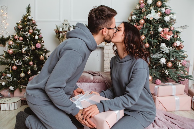 Mooi paar zittend zoenen open geschenken presenteert slingers thuis gezellige interieur sfeer