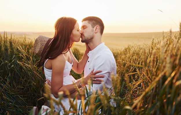 Mooi paar zoenen en vrije tijd doorbrengen op het veld op zonnige dagtijd van de zomer