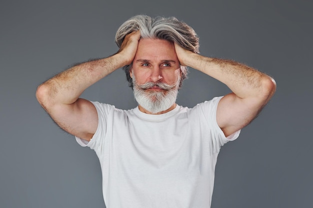 Mooi portret Stijlvolle moderne senior man met grijs haar en baard is binnenshuis