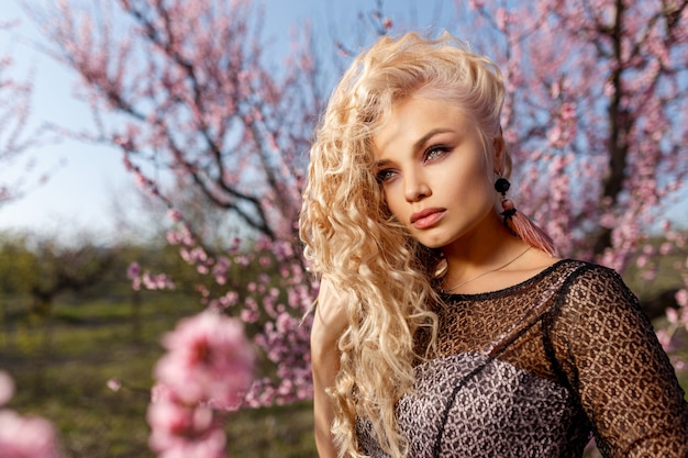 Mooi portret van een vrouw in een tuin van bloeiende perziken