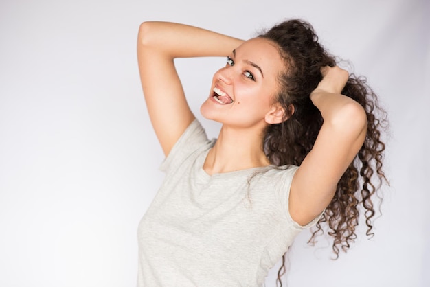 Mooi portret van jonge brunette vrouw flirt met krullend haar en een tong