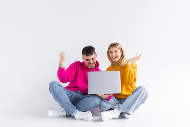 Mooi portret van paar met laptop dat grijze achtergrond gaat zitten