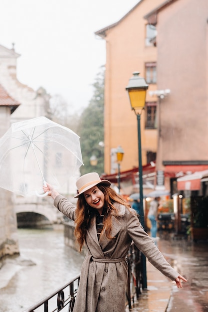 Mooi romantisch meisje in een jas en hoed met een transparante paraplu in Annecy