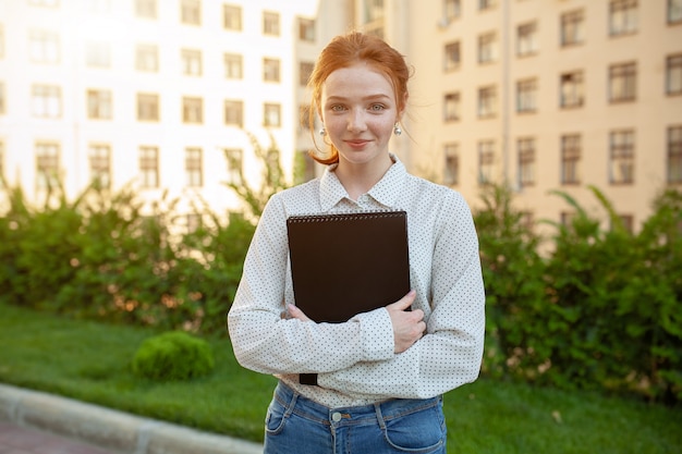 Mooi rood haired meisje met sproeten die notitieboekjes koesteren