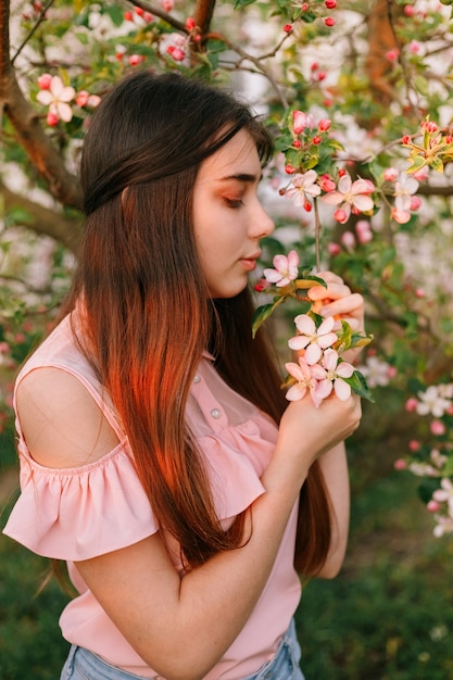 Mooi roodharig meisje in de lente in de takken van de appelboom