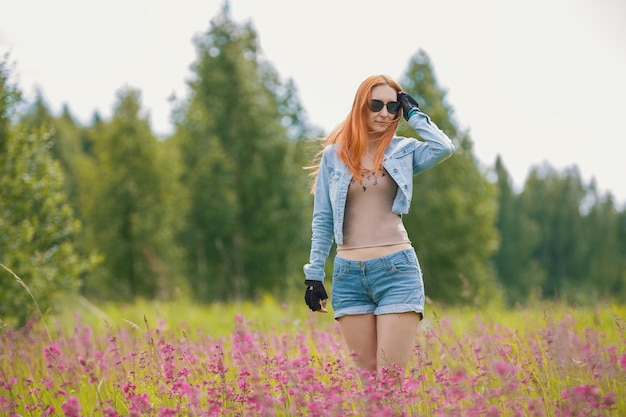 Mooi roodharig meisje in een bloemenveld, zomer