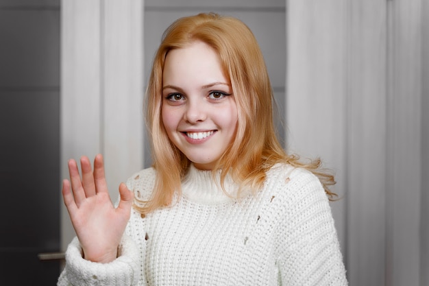 Foto mooi roodharig meisje zwaait verlegen met haar hand. uitdrukking van emotie