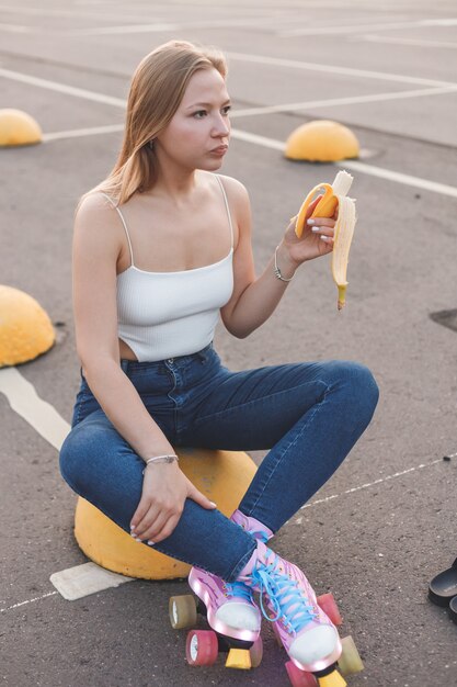 Mooi schattig helder meisje op een turkooizen achtergrond lacht houdt een tros bananen vast en eet ze op...