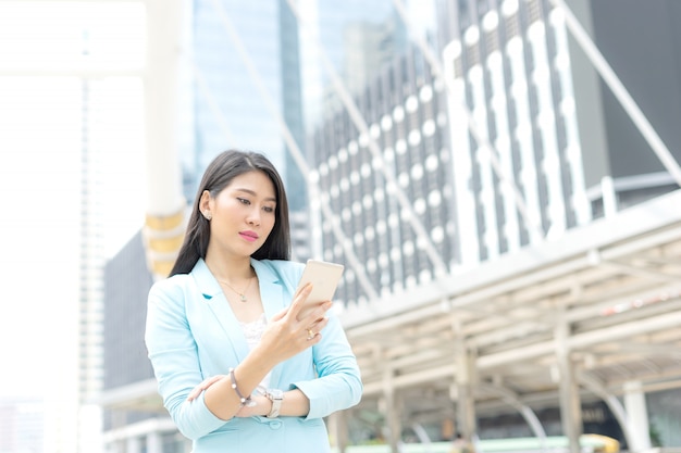 Mooi schattig meisje in zakelijke vrouw kleding met behulp van slimme telefoon computer business concep