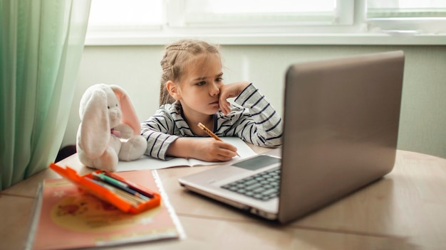 Mooi schoolmeisje studeert huiswerk wiskunde tijdens haar online les thuis online onderwijs concept