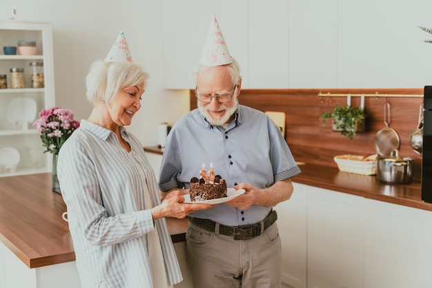 Mooi senior paar dat jubileum viert met verjaardagstaart - Bejaard echtpaar met verjaardagsfeestje thuis