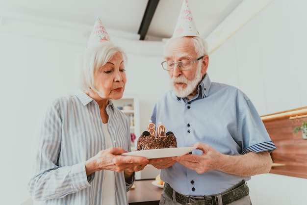 Mooi senior paar dat jubileum viert met verjaardagstaart - bejaard echtpaar met verjaardagsfeestje thuis