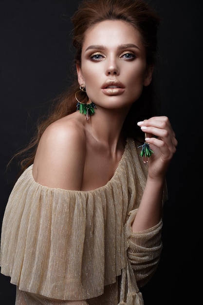 Mooi sexy meisje met sensuele lippen, mode haar, gouden jurk en accessoires. Mooi gezicht. Foto genomen in de studio