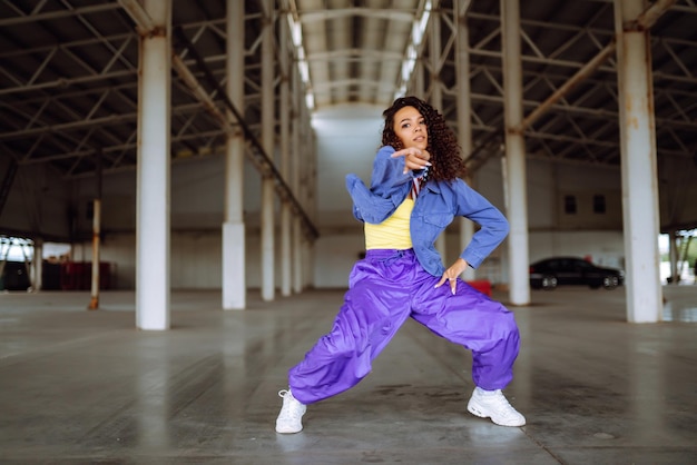 Mooi sportief meisje dansen in stijlvolle kleding in de onderdoorgang Sportdansen en stedelijke cultuur