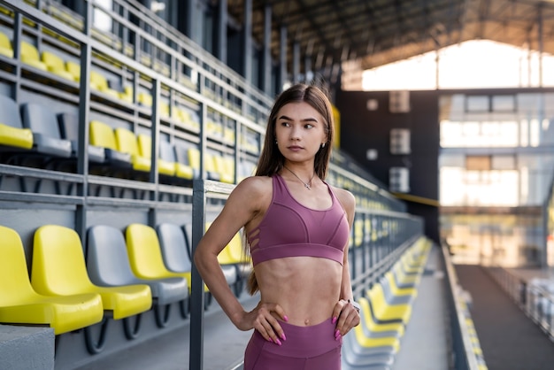 Mooi sportief meisje met rust in de buurt van zit op het stadion op zonnige dag