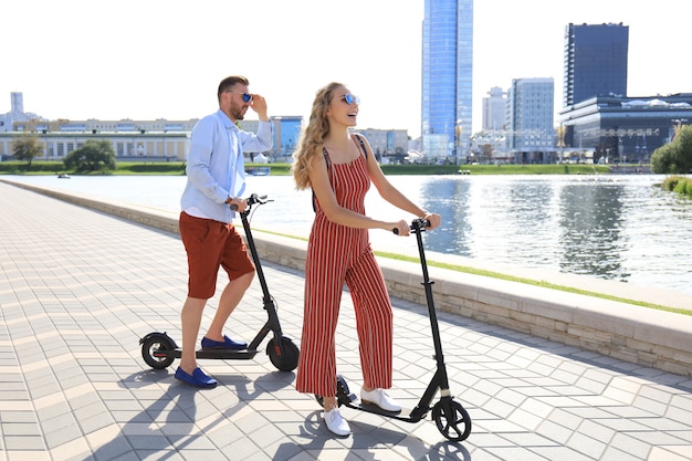 Mooi stel dat plezier heeft met het besturen van een elektrische scooter langs de stadspromenade.