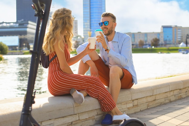 Mooi stel dat plezier heeft met het rijden op een elektrische scooter door de stad met een pauze om koffie te drinken