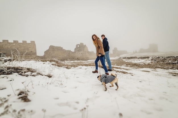 Mooi stel in het winterveld tijdens een wandeling met de hond. Hond wandelen met eigenaar buiten besneeuwde natuur.