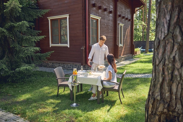 Foto mooi stel terwijl ze ontspannen in de groene tuin van hun moderne luxe huis