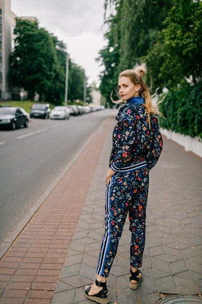 Mooi stijlvol blond model in gekleurd pak poseren in de straat