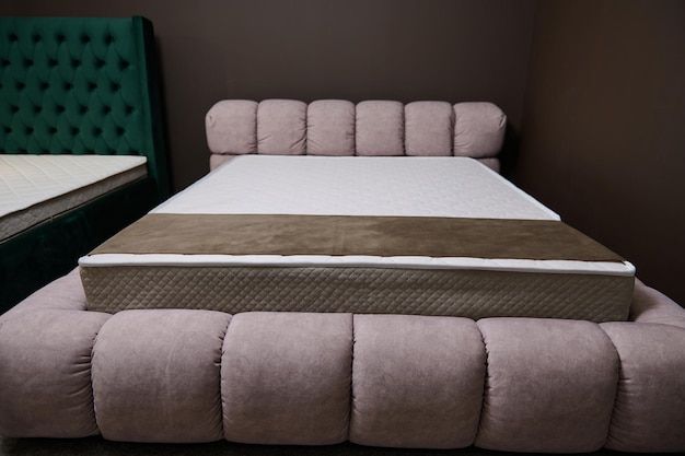 Mooi stijlvol roze zacht bed met een orthopedische harde matras tentoongesteld in de showroom van een meubelwinkel die te koop wordt aangeboden