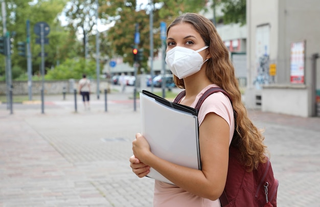 Mooi studentenmeisje met beschermend masker terug naar school na pandemisch coronavirus