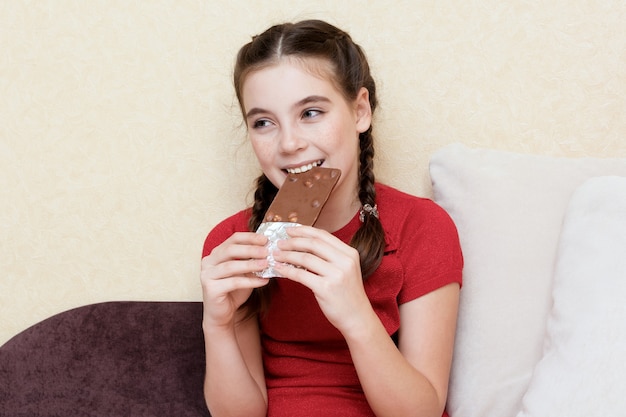 Foto mooi tienermeisje dat chocoladereep eet en glimlacht.