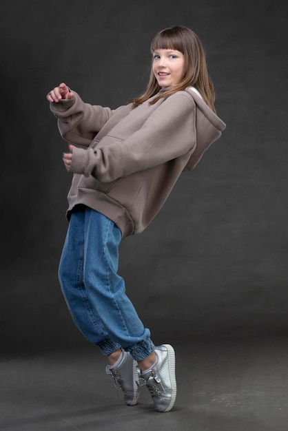 Mooi tienermeisje in een sweatshirt en jeans danst