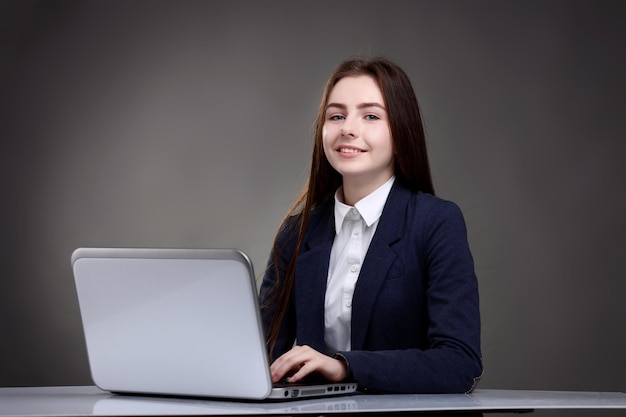 Mooi tienermeisje zit aan tafel met laptopStuderen