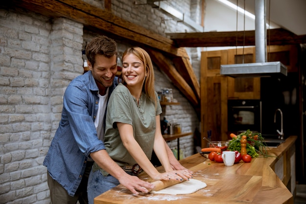 Mooi vrolijk jong paar dat diner samen voorbereidt en pret heeft bij rustieke keuken